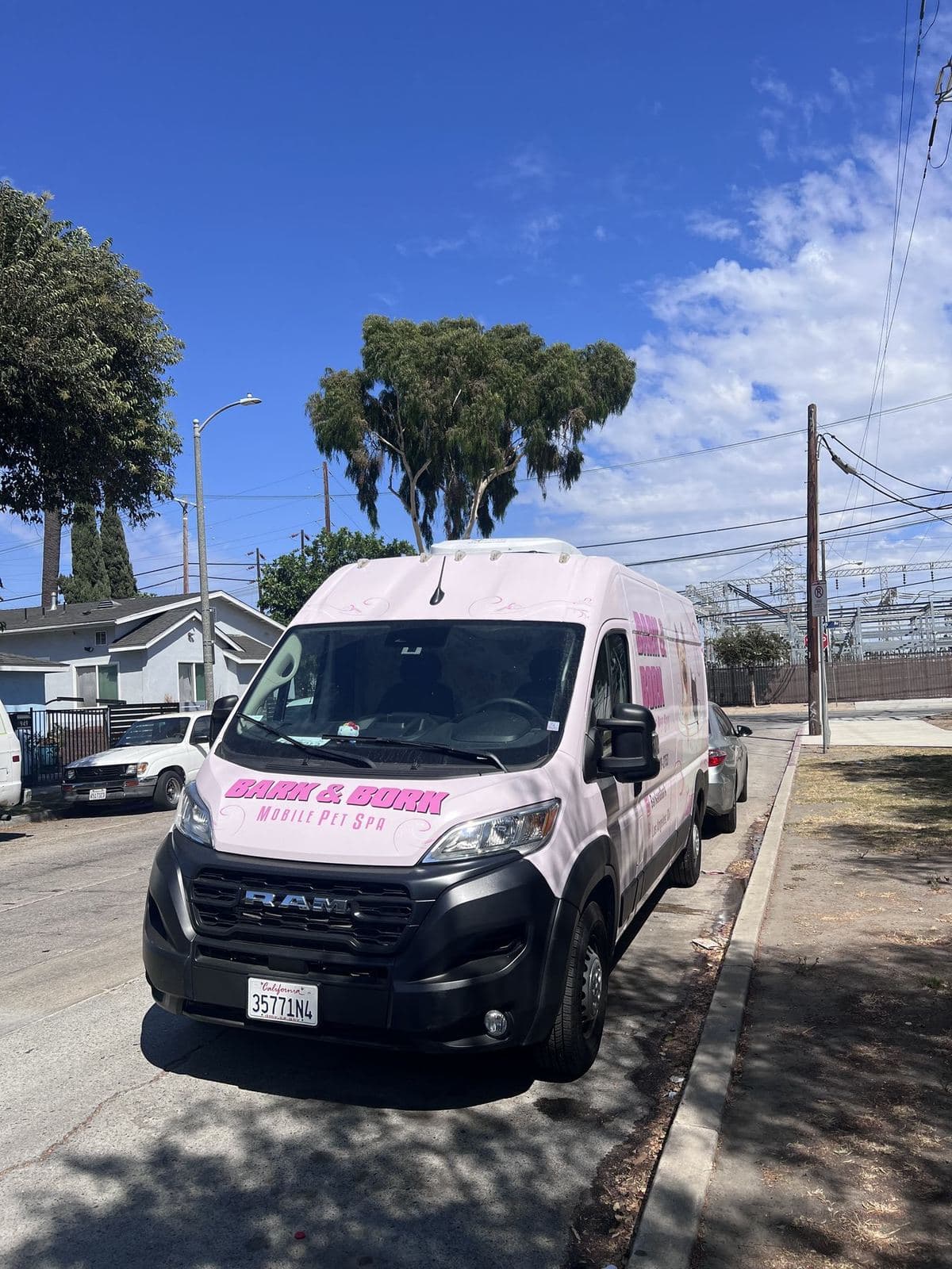 Front three-quarter view of the Bark and Bork mobile grooming van parked on a residential Los Angeles street