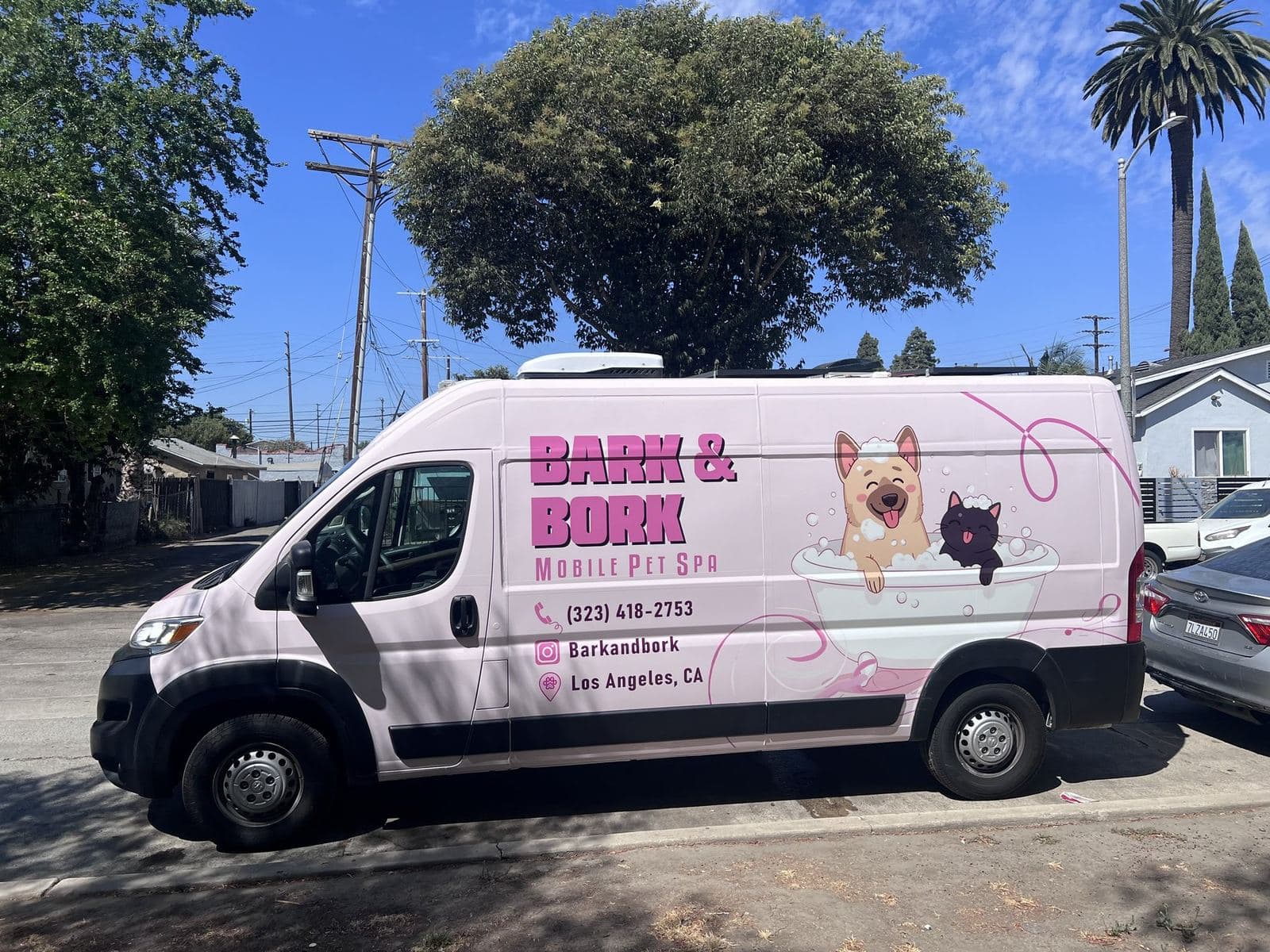 The Bark and Bork mobile pet spa van parked on a shaded Los Angeles street, showing the full side brand wrap