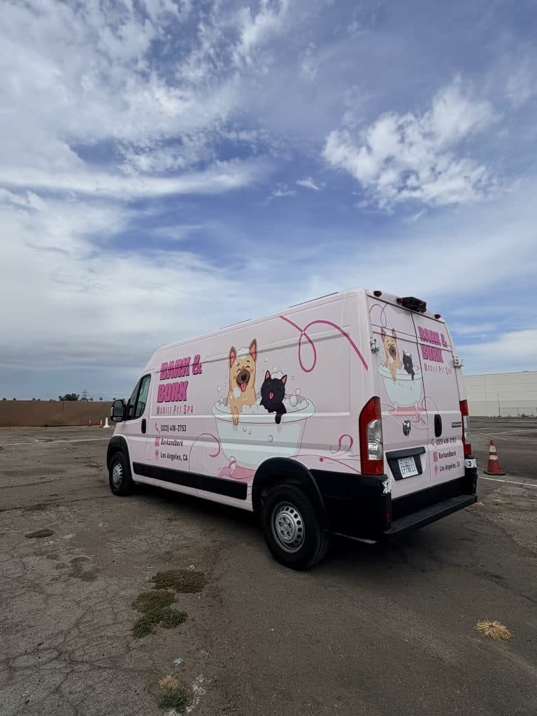 Rear three-quarter view of the Bark and Bork mobile grooming van showing the full brand wrap
